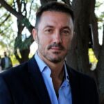 Luis Petri sostiene un mate con la inscripción Milei 2027 en una muestra de Luis Petri apoya a Milei.